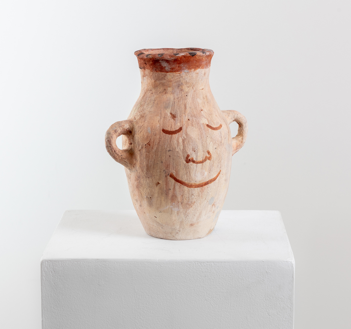 A pot with handles for ears and a face painted on